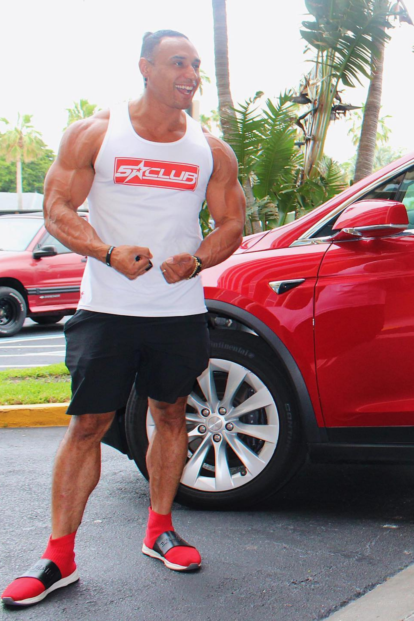 men wearing 5 star club white Tank Top and standing near red car